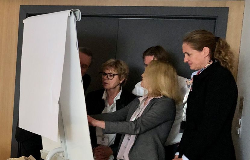 Einige Menschen stehen vor einem Flipchart und diskutieren