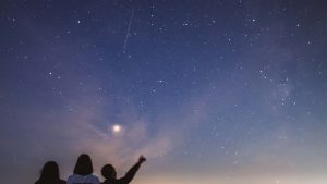 Eine Gruppe von Menschen bestaunen einen Nachthimmel und zeigen auf die Sterne, eine Welt im Wandel